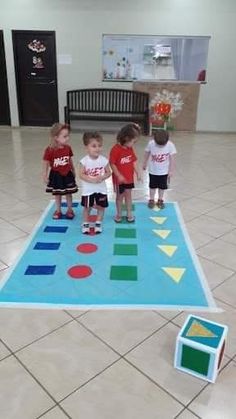 four children standing in front of a play mat on the floor