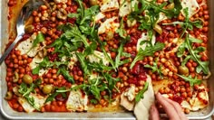 a pizza covered in lots of toppings on top of a pan