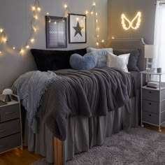 a bedroom decorated in gray and white with lights on the wall above the headboard