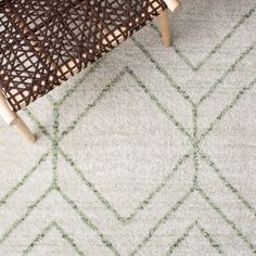 a white rug with green lines on it and a wooden chair next to it in front of a window