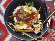 a black plate topped with meat and vegetables