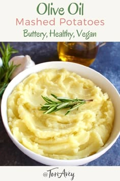 a bowl filled with mashed potatoes next to a bottle of olive oil and a sprig of rosemary