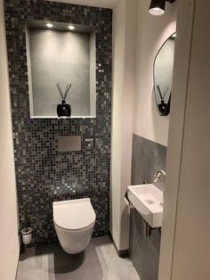 a bathroom with a toilet, sink and mirror in it's corner stall area