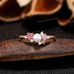 a pink and white pearl ring on top of a piece of wood