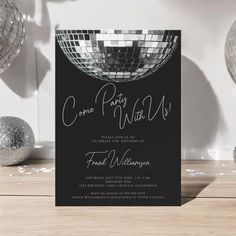 a black and white party card with silver disco ball on the front, and confetti in the back