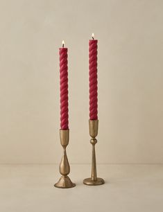 two red candles are standing next to each other