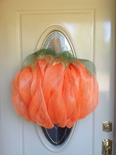 an orange mesh pumpkin hanging on the front door to decorate it's entryway