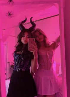 two young women are taking a selfie in front of a mirror with horns on it