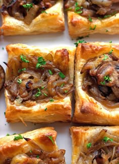 several square pastries with mushrooms and parsley in them on a white plate, ready to be eaten