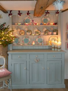 a china cabinet with plates and candles on it in a room filled with christmas decorations