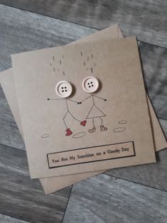 two greeting cards with buttons attached to them