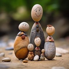 a group of rocks with faces on them sitting next to each other in the sand