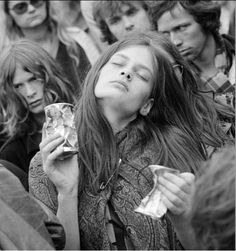 black and white photograph of woman eating food with other people watching from the sidelines