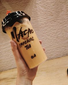 a person holding up a cup with writing on it