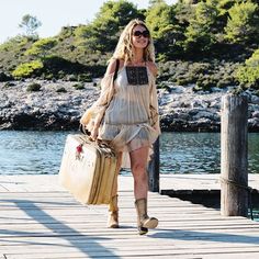 a woman walking across a pier carrying luggage