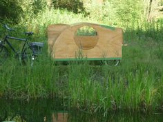 a bike is parked next to a wooden structure in the middle of some grass and water