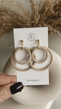 a pair of beige hoop earrings sitting on top of a white plate next to a plant