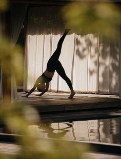 a person doing a handstand in front of a pool with curtains behind them