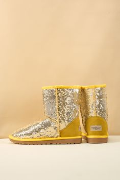 Spice up your shoe game with Smaibulun Ugg's Dallas Glam Sequin Shearling Boots! The perfect blend of style and comfort, these boots feature playful yellow glam sequins and cozy shearling lining. Who says ugg footwear has to be boring? (No one, that's who!) 1'' heel 7.6'' shaft 15.8'' circumference Pull-on Suede upper & Man-made sequins Faux fur lining EVA sole Trendy Yellow Winter Boots, Gold Boots With Round Toe For Winter, Reindeer Headband, Shearling Boots, Eva Sole, Daily Dress, Dress Jewelry, Shoe Game, Ugg Shoes