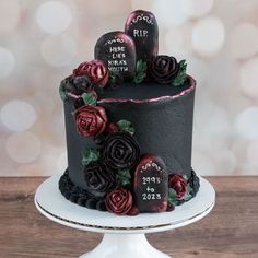 a three tiered cake decorated with roses and tombstones on a plate, sitting on a wooden table