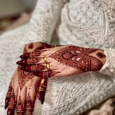 a woman's hands with hennap and jewelry on her arm, wearing a wedding dress