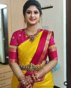 a woman in a yellow and red sari with her hands on her hips, posing for the camera