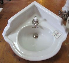 a white bathroom sink sitting on top of a wooden floor next to a faucet