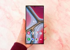 a person holding an lg smartphone in their hand on a pink marble table top