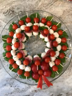 a glass plate topped with tomatoes and skewered meats on toothpicks