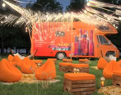 an orange food truck is parked in the grass with firecrackers on it