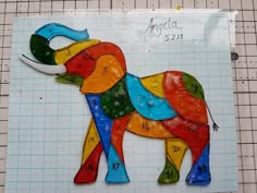 an animal made out of colored glass sitting on top of a piece of construction paper