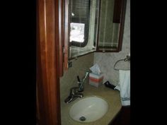 a bathroom sink sitting under a window next to a towel dispenser on a counter