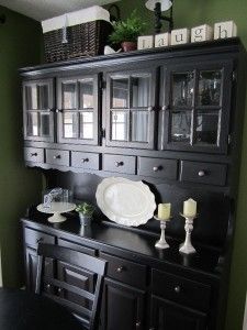 a black china cabinet with plates and candles