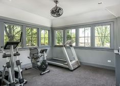 an exercise room with treadmills and windows