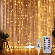 a remote control sitting on top of a wooden floor next to a window covered in lights