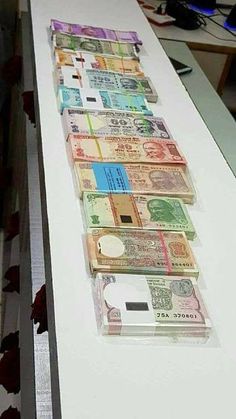 several stacks of money sitting on top of a white counter next to a laptop computer