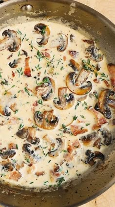 a pan filled with mushrooms and sauce on top of a wooden table