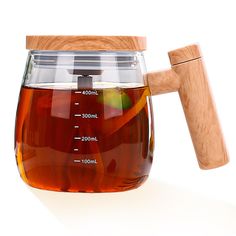 a glass teapot filled with liquid and a wooden handle for measuring the amount of water in it