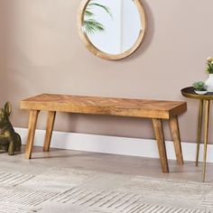 a wooden bench sitting in front of a mirror on a wall next to a table