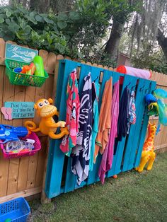 there is a wooden fence with clothes hanging on it and toys in the back ground