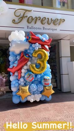 balloons in the shape of an airplane and number five are on display outside a store