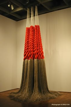 an art installation consisting of red and white yarn wrapped in long, brown hair on top of a wooden floor