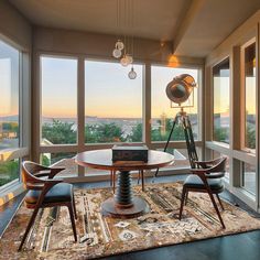 a living room filled with furniture and large windows overlooking the cityscape in the distance