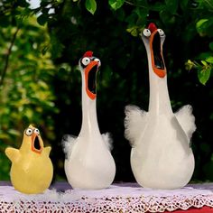 three white birds with orange beaks on a table