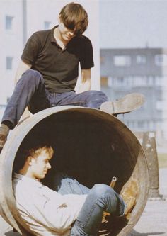 two young men sitting in an old barrel