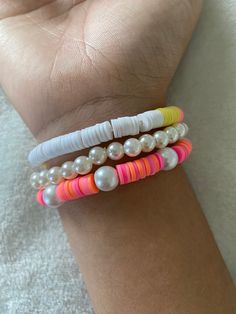 three different colored bracelets on someone's wrist with pearls and beads attached to them