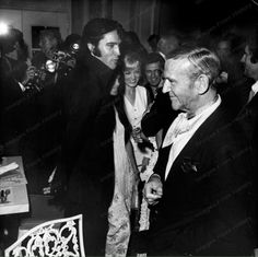 an old black and white photo of two men shaking hands with other people in the background