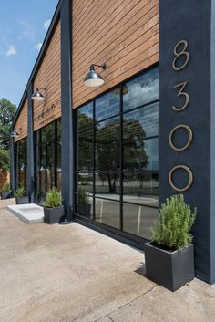 the outside of a building with large windows and planters on the sidewalk in front