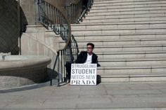 a man sitting on steps holding a sign that says struggling student needs new prada