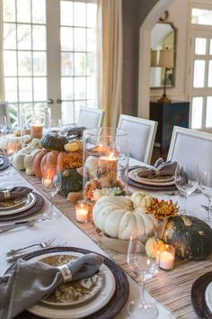 a dining room table is set with pumpkins and candles